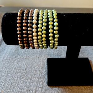 Beaded bracelets . Eight (8) total four green , one white three brown